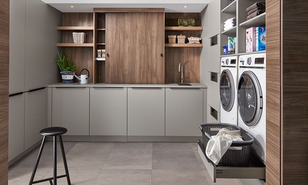 Minimalistische bijkeuken met grijze opbergkasten.