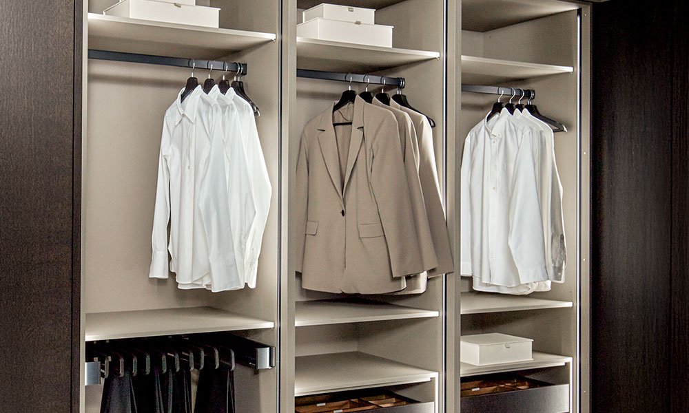 Dressing moderne avec tringle à vêtements et blazers suspendus avec soin.
