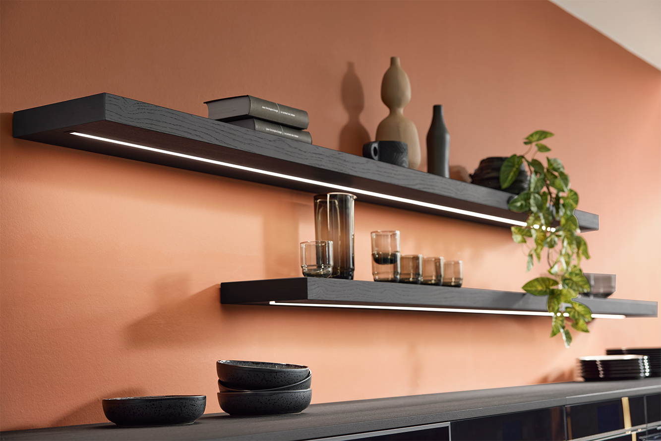 Floating wooden shelves with integrated LED lighting – elegant kitchen feature set against a terracotta wall.