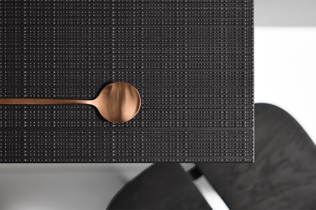 Detail einer strukturierten Küchenoberfläche in dunkler Boho Optik mit kupferfarbenem Löffel – elegantes Designstatement.