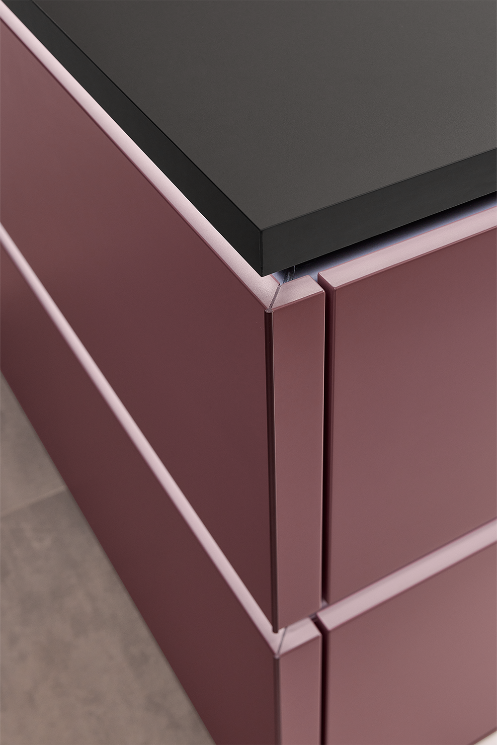 Pronorm Küche in einem roten velvet Ton mit horizontal beleuchteten Griffleisten der Kücheninsel.