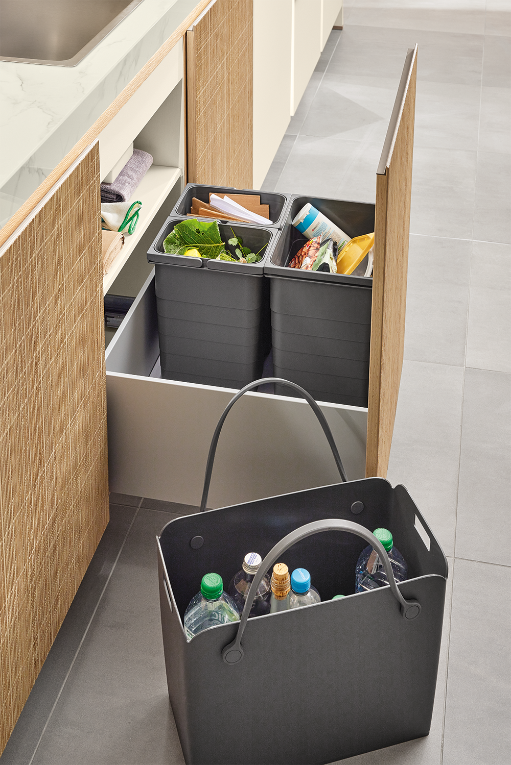 Integrated waste separation system in Y-line Boho kitchen featuring a pull-out drawer with multiple recycling bins and natural rattan-style front