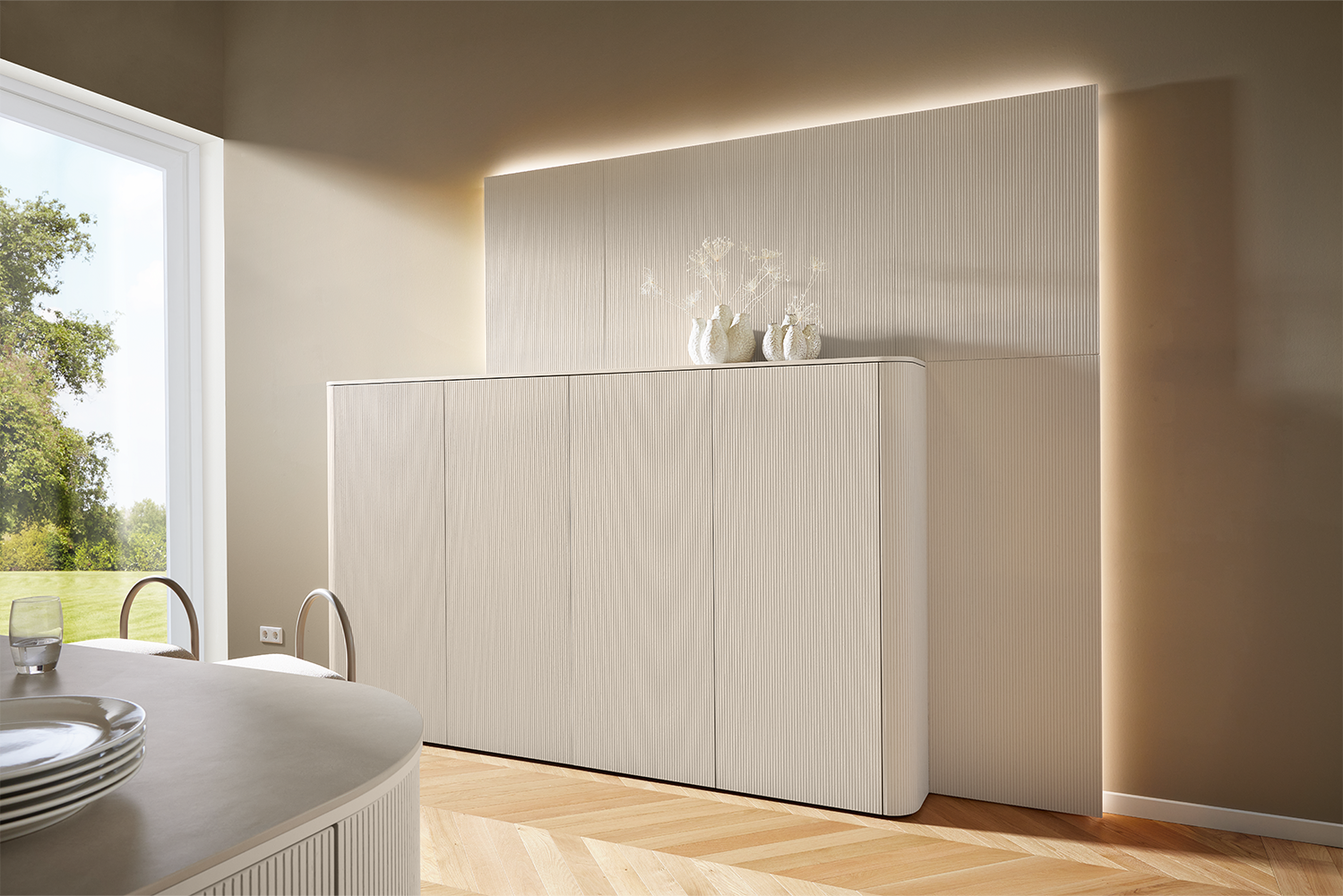 Pronorm living furniture with rounded corners, matching the kitchen front in Angora grey with a ribbed texture.