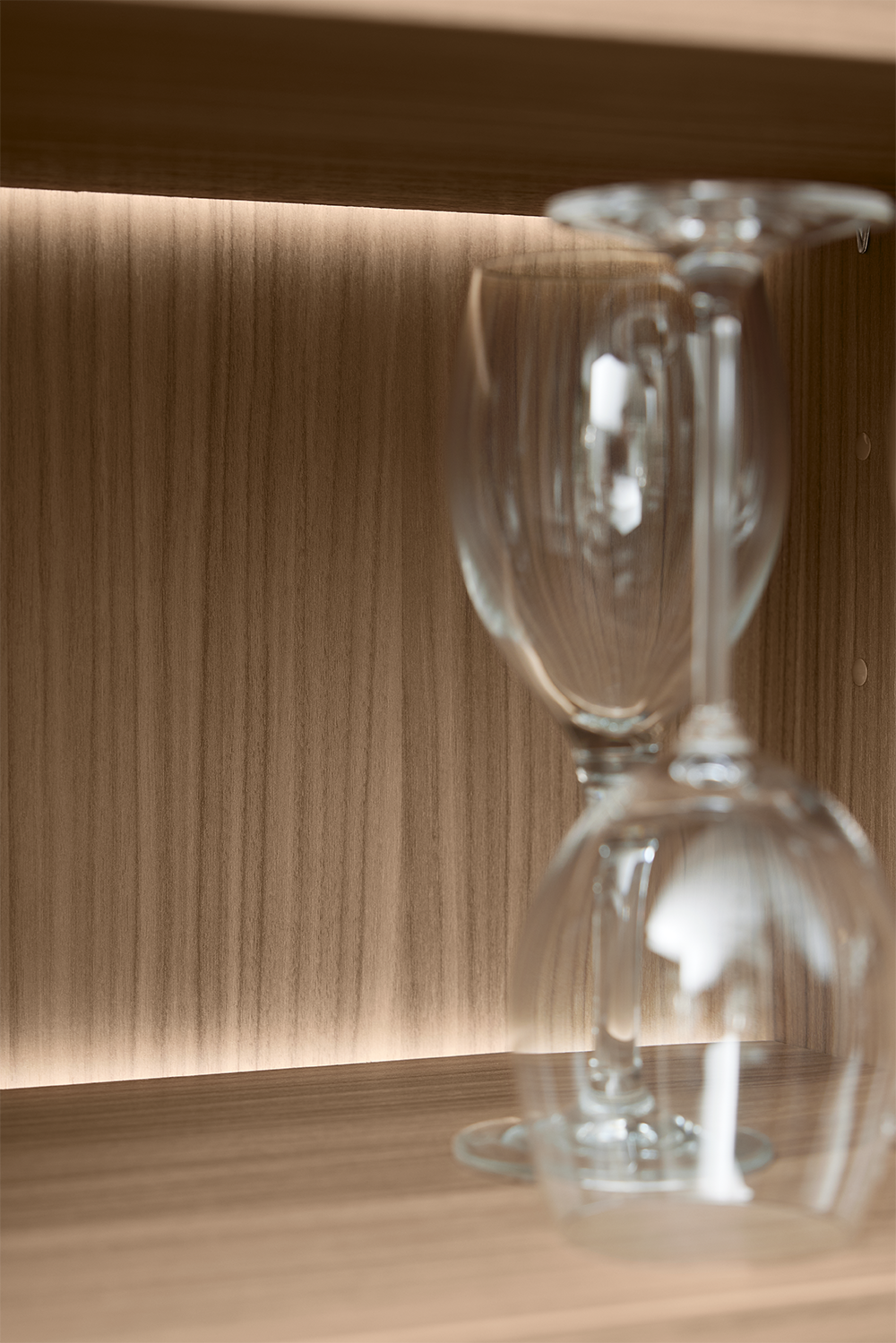 Subtle warm LED strip light adds ambient glow to the back panel of a wood-finished kitchen cabinet