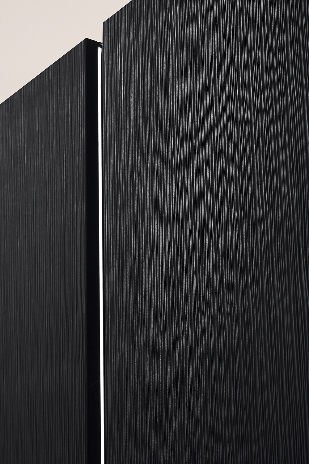 Façade en placage noir d’une cuisine pronorm avec profil de prise éclairé verticalement.