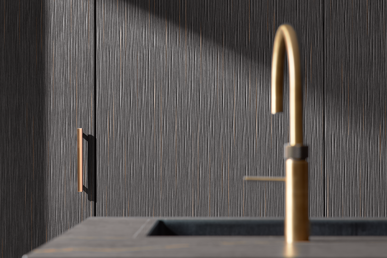 Detailansicht einer strukturierten pronorm Küchenfront mit vertikaler Maserung und goldener Armatur – edles Materialspiel in dunklem Holz.