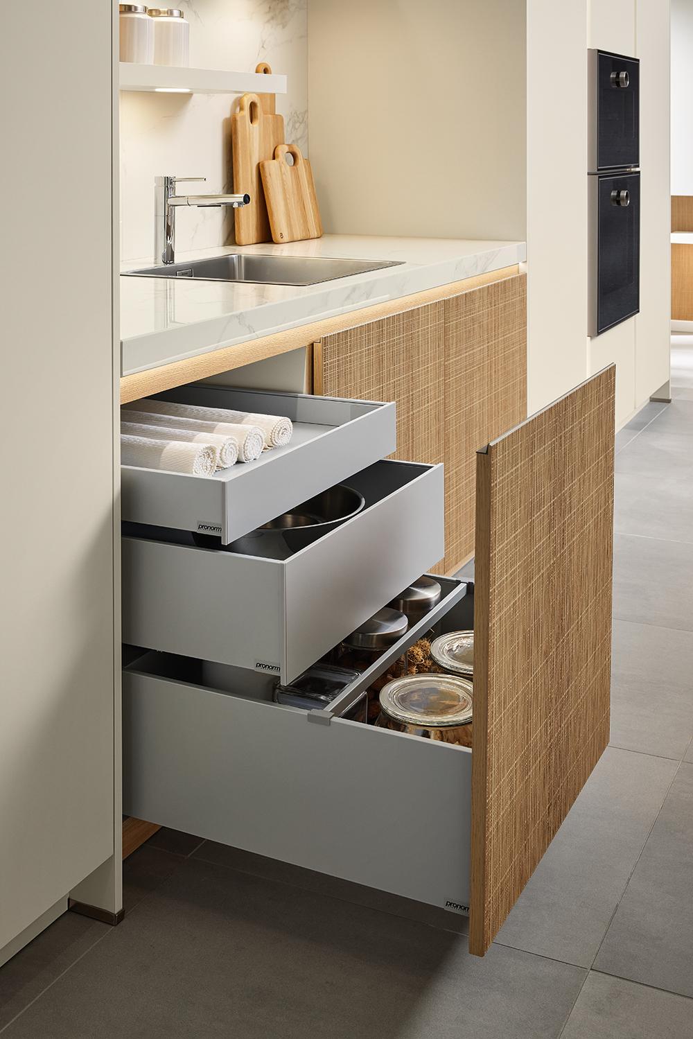 Open Y-line drawers in Boho-style kitchen showcasing premium storage organisation with soft-close system and natural rattan-look fronts
