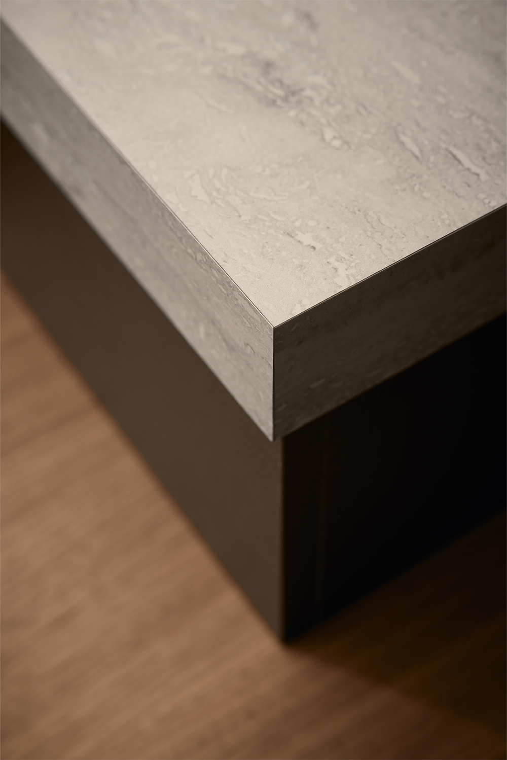 Close-up of light stone-look worktop with dark units and walnut accent in a modern handleless kitchen by pronorm