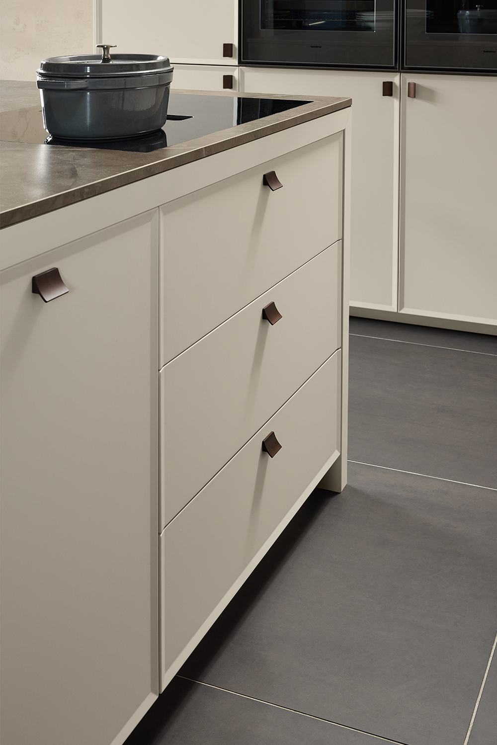 Modern country kitchen drawers with sleek shaker fronts and dark handles in soft grey tones
