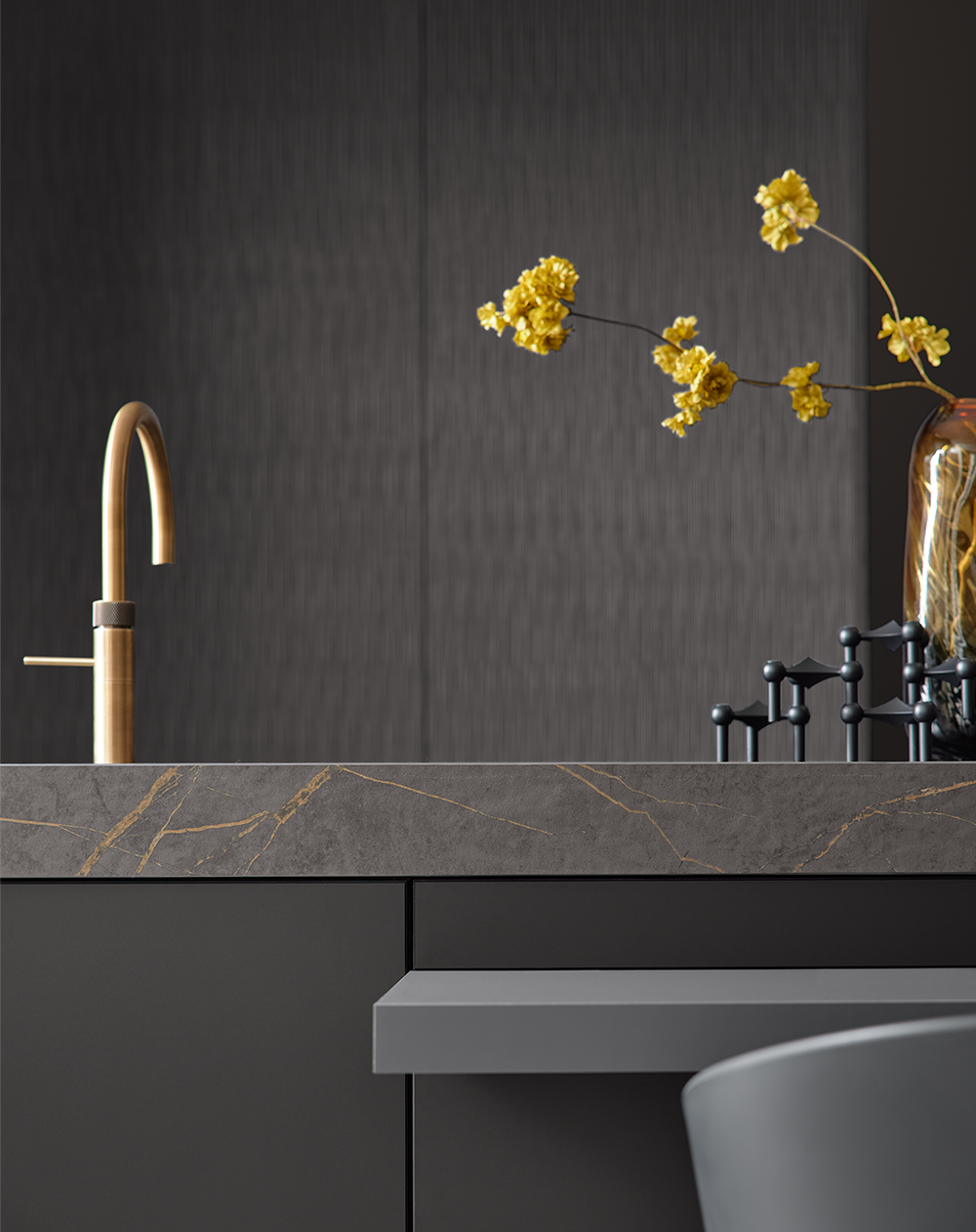 Designküche von pronorm mit goldener Armatur, dunkler Front und markanter Steinarbeitsplatte mit goldenen Adern – modernes Küchendesign im Detail.