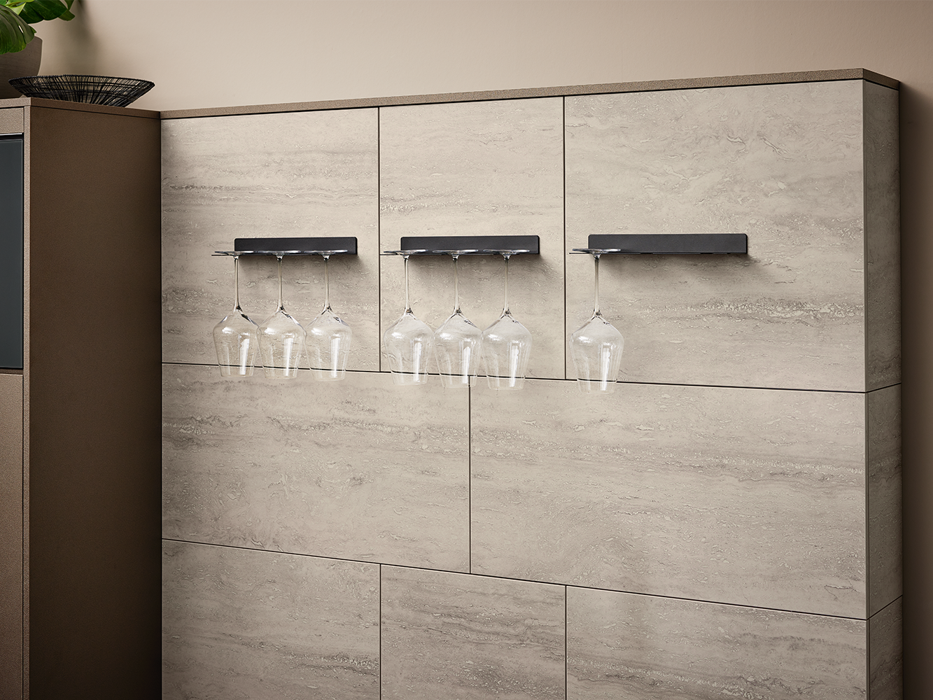 Overzicht van zwarte wijnglashouders met glazen aan een wand in steenlook, onderdeel van greeploze designkeuken van pronorm