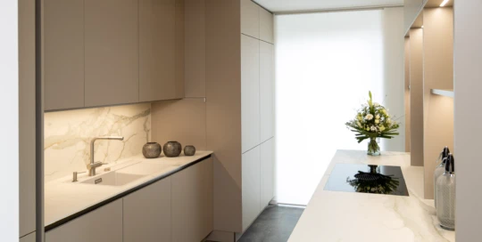 Helle moderne pronorm Küche mit Marmoroberfläche und klarer Architektur.