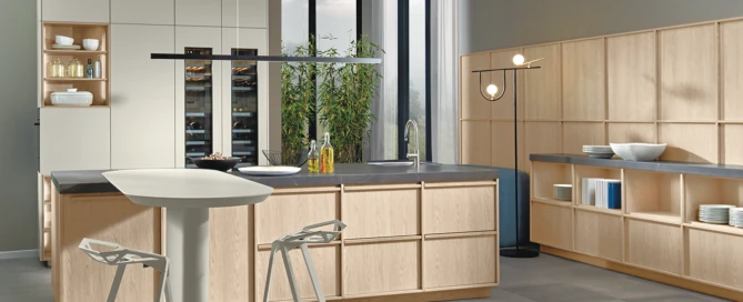 A Japandi-style kitchen by pronorm with framed fronts in light oak, a dark worktop, and matt lacquer tall units. The island with attached table is also practical.