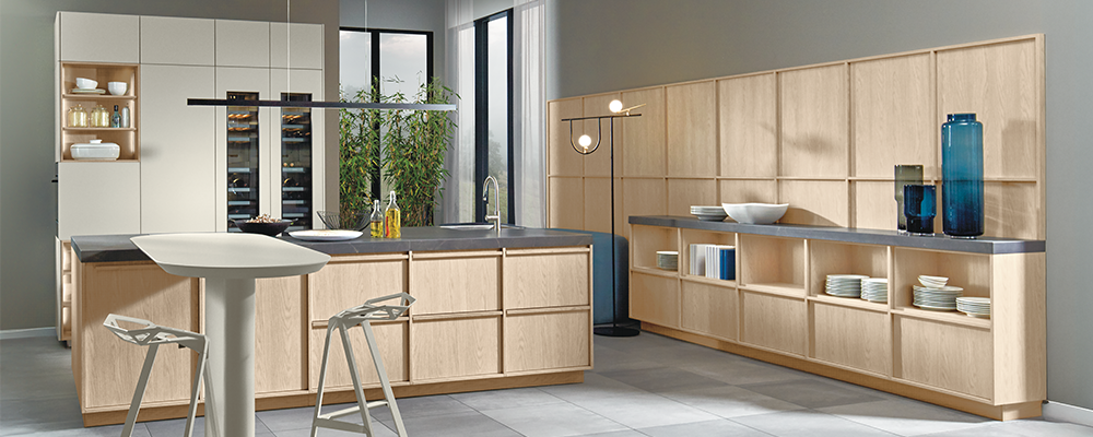 Eine Küche mit Regal im Japandi Stil. Die Fronten in Eiche Kaschmir spiegeln sich auch hinter dem Regal als Wandverkleidung wider und bilden ein harmonisches Gesamtbild.