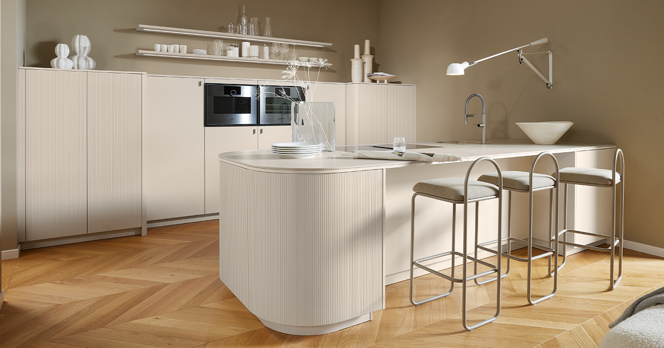 Îlot de cuisine pronorm avec îlot arrondi en gris Angora et façade verticalement rainurée en chêne gris Angora, design de cuisine moderne avec plaque à induction et espace bar