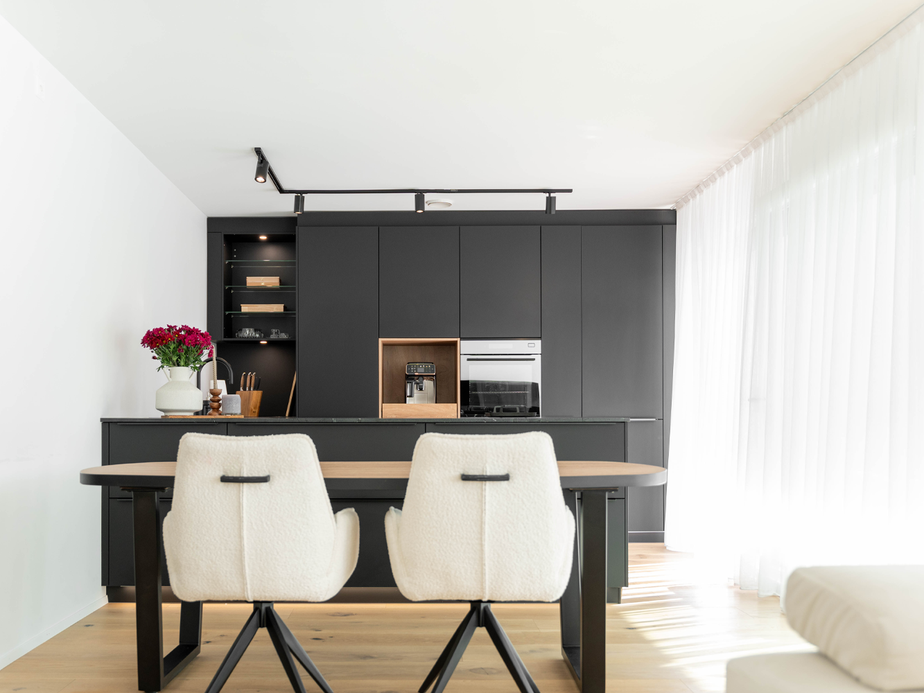 Elegante inbouwkeuken in zwart met warme houtfronten en modern kookeiland – hoogwaardige materialen voor tijdloos design.