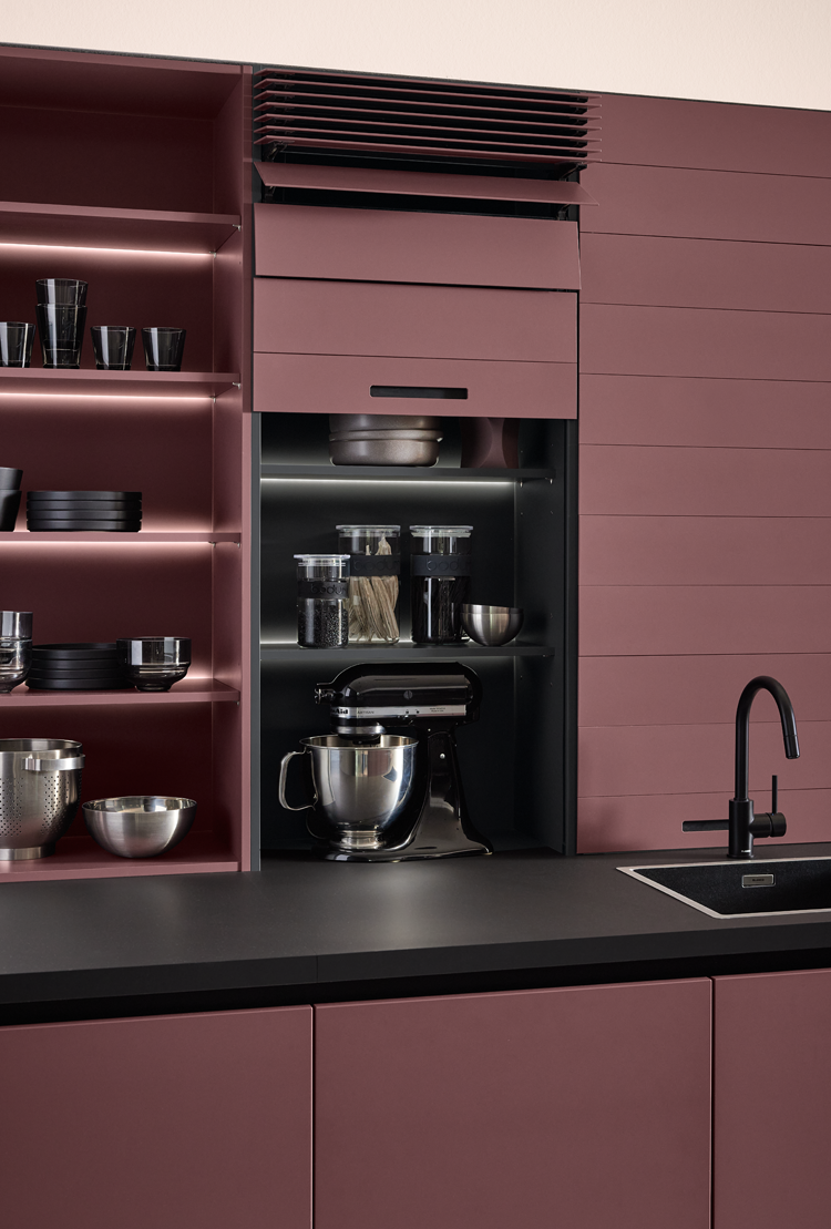 Cuisine pronorm moderne avec flipdoor, espace de rangement généreux, étagères éclairées et plan de travail noir.