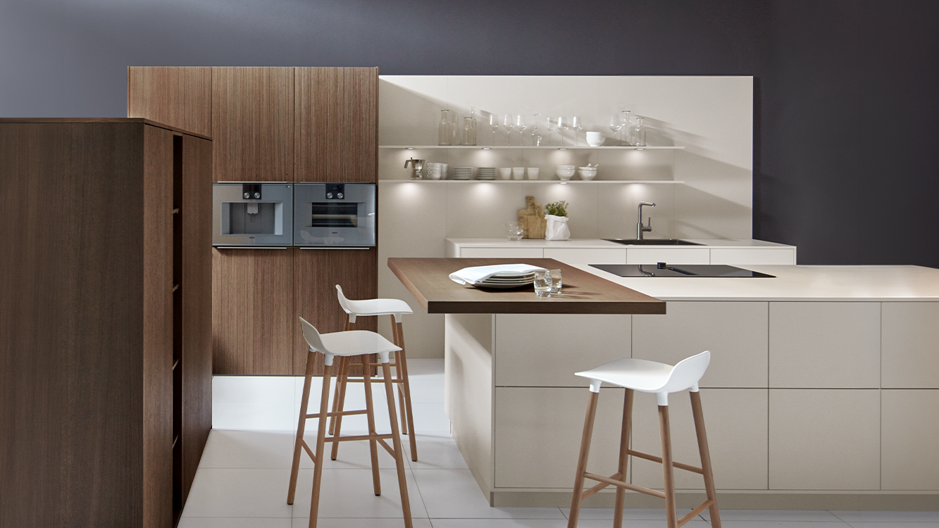 Bright handleless pronorm kitchen with wood elements and a kitchen island with seating.