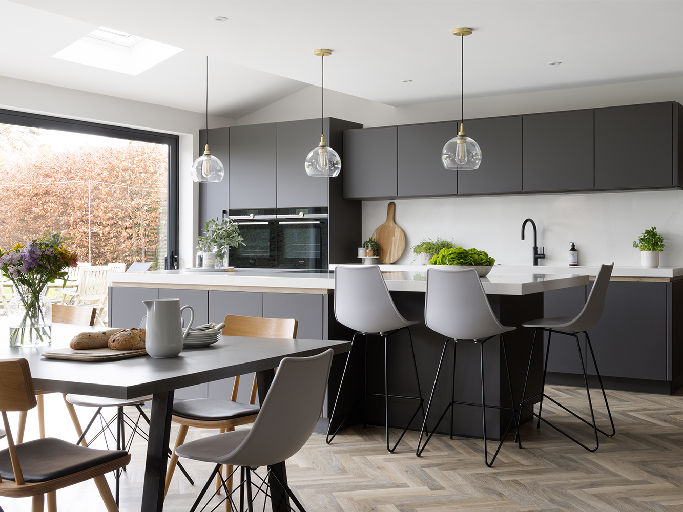 A dark grey pronorm kitchen, very high quality, with a kitchen island and seating area.