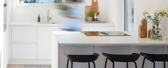 A bright, white modern handleless pronorm kitchen with tall units and a kitchen island with bar stools.
