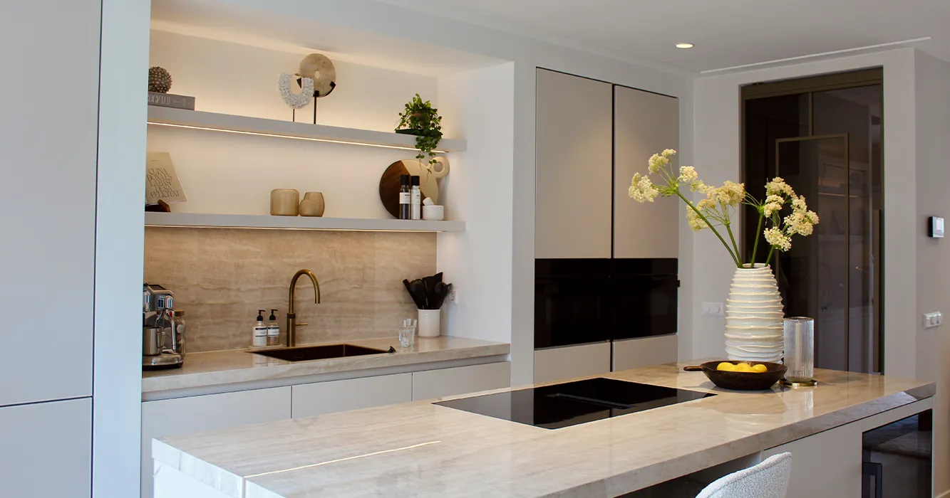 Cuisine Pronorm lumineuse couleur gris Angora avec niche et étagères murales assorties et îlot central.