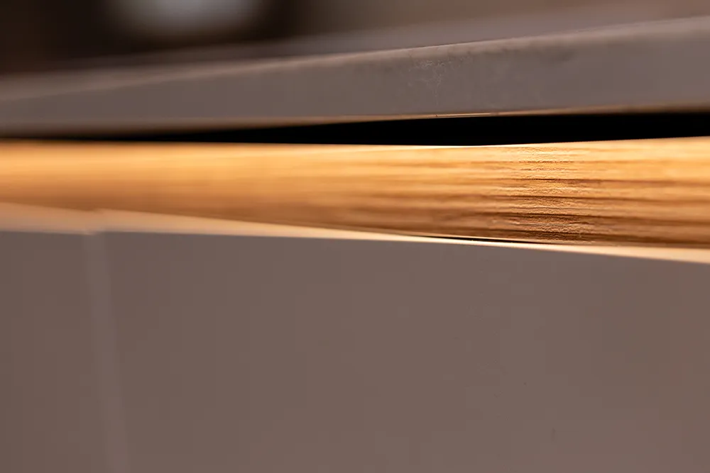Détail d’une cuisine scandinave pronorm avec éclairage LED intégré sur le bord de façade.