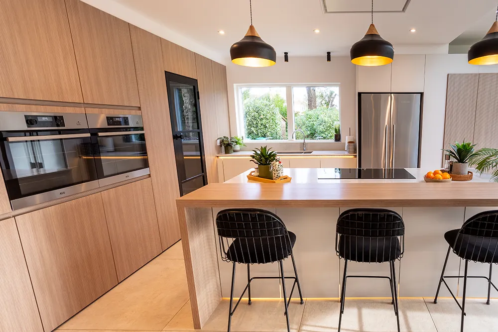 Cuisine équipée scandinave de pronorm avec façades bois, îlot central et tabourets de bar.