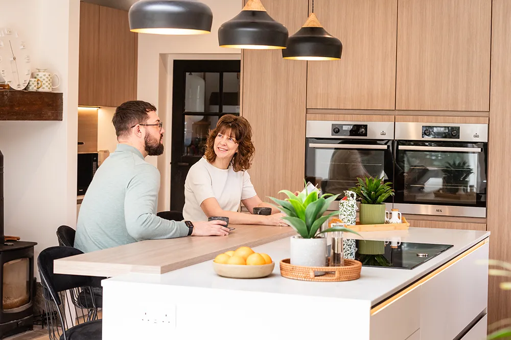 Moderne pronorm Skandi-Wohnküche mit Kücheninsel, Frühstückstheke und schwarzen Barhockern.