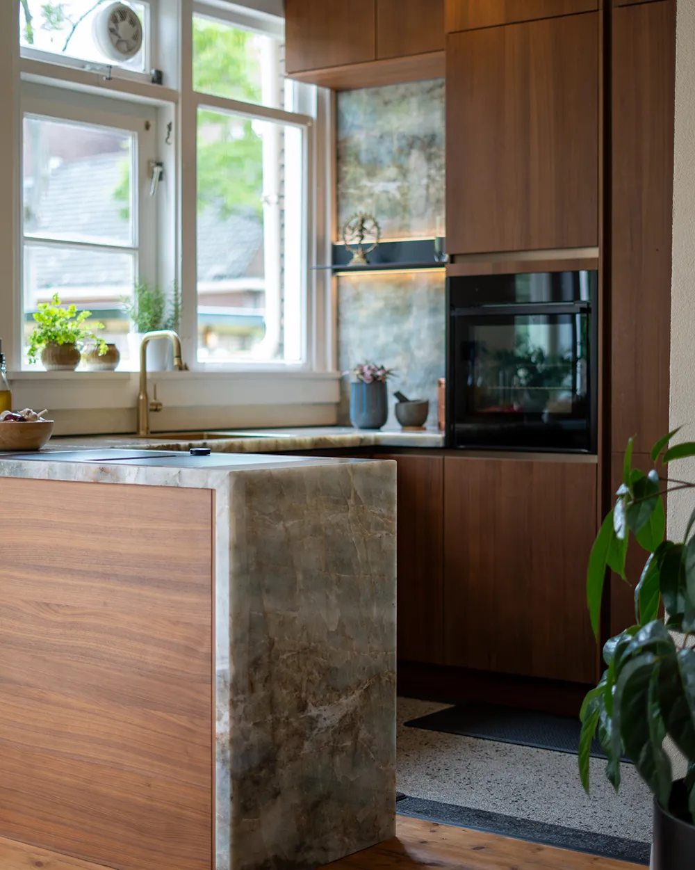 Grifflose Nussbaumküche mit deckenhohen Schränken, Naturstein-Arbeitsplatte und integrierten Elektrogeräten von pronorm.
