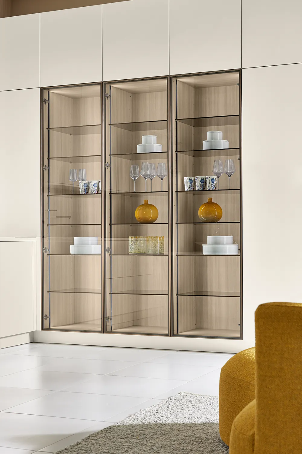 Helle grifflose Küche von pronorm mit Vitrine und Glasrahmentüren.